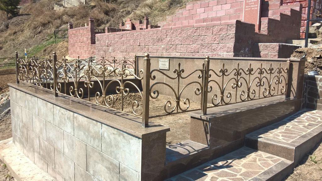 Обзор могилы с установленной простой и элегантной оградкой